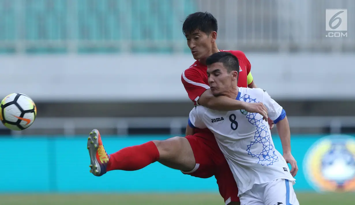 Gelandang Uzbekistan, Kenjabaev Islom (depan) berebut bola dengan pemain Korea Utara pada laga perdana PSSI Anniversary 2018 di Stadion Pakansari, Kab Bogor, Jumat (27/4). Laga berakhir imbang 2-2. (Liputan6.com/Helmi Fithriansyah)