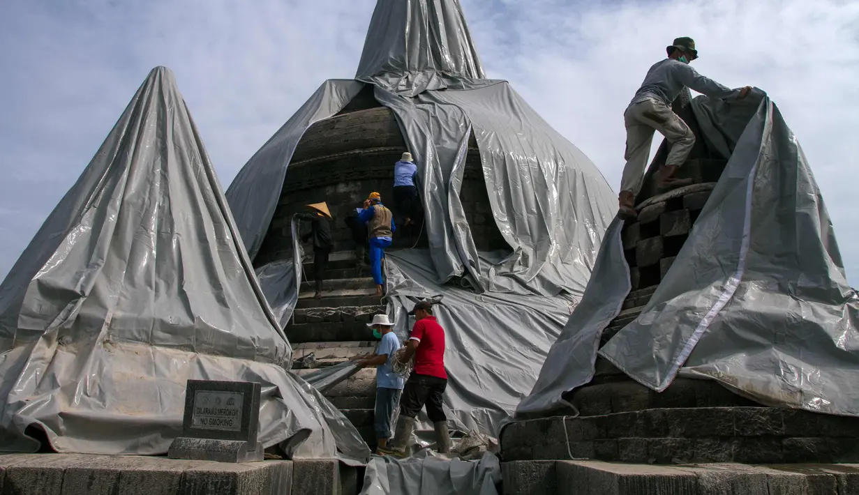 Relawan melepaskan penutup pelindung dari stupa candi Borobudur di Magelang, provinsi Jawa Tengah pada 17 Februari 2014 untuk memulai pembersihan endapan abu vulkanik menyusul letusan gunung berapi Gunung Kelud. (AFP Photo/Suryo Wibowo)