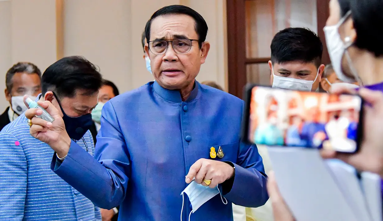 PM Thailand, Prayut Chan-O-Cha menyemprotkan pembersih tangan ke wartawan untuk menghindari pertanyaan perombakan kabinet selama konferensi pers di Bangkok, Selasa (9/3/2021). Sebelum menyemprot, Prayuth mengatakan kepada wartawan untuk mengurus urusan mereka sendiri. (HO/ROYAL THAI GOVERNMENT/AFP)