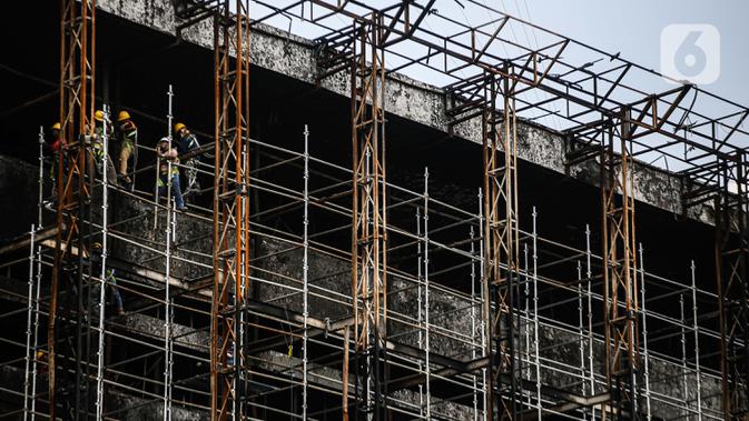 Pekerja memasang 'scaffolding' atau struktur besi untuk melakukan perbaikan Gedung Kejaksaan Agung, Jakarta, yang hangus terbakar, Rabu (7/10/2020).  DPR RI menyepakati penambahan anggaran Kejagung sebesar Rp 350 miliar untuk merenovasi gedung utama yang terbakar hebat. (Liputan6.com/Faizal Fanani)