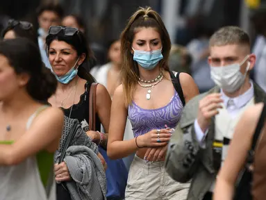 Pembelanja yang mengenakan masker berjalan di sepanjang Oxford Street di pusat kota London, Senin (5/7/2021). PM Inggris Boris Johnson berencana mencabut sebagian besar pembatasan wilayah selama pandemi Covid-19, termasuk penggunaan masker dan jaga jarak mulai 19 Juli. (DANIEL LEAL-OLIVAS/AFP)