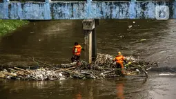 Petugas PPSU membersihkan sampah yang tersangkut di tengah derasnya aliran Kali Ciliwung, Jakarta, Rabu (19/5/2021). Pembersihan tersebut dimaksudkan agar tidak ada penumpukan sampah dan sedimentasi saluran di sepanjang Kali Ciliwung. (Liputan6.com/Faizal Fanani)