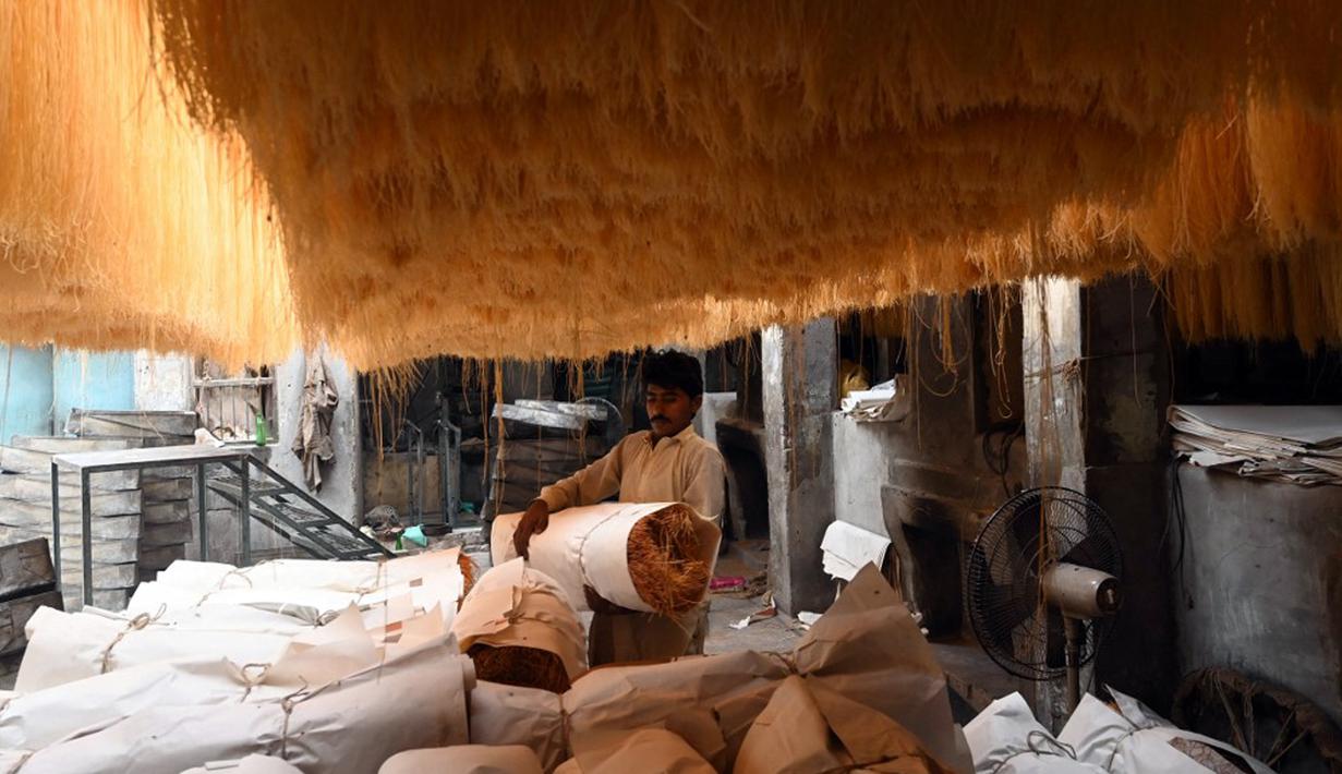 Seorang pekerja mengemas bihun yang digunakan untuk membuat hidangan manis tradisional yang populer selama bulan puasa Ramadhan, di Lahore pada 12 April 2022. (Arif ALI/AFP)