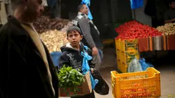 Mohammad al-Bana (10), Bocah Palestina menjual sayur di sebuah pasar di Kota Gaza (29/3). Bana yang masih bersekolah menghasilkan sekitar sekitar 10 Shekels ($ 2.5) per hari karena ayahnya sudah lagi tidak bekerja. (REUTERS/Mohammed Salem)