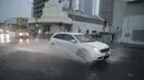 Sebuah mobil berbelok ke Cooke Street yang banjir di Honolulu (6/12/2021). Badai kuat yang membawa angin kencang dan hujan yang sangat deras membanjiri jalan-jalan dan meruntuhkan kabel listrik dan cabang-cabang pohon di seluruh Hawaii. (AP Photo/Marco Garcia)