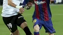 Penyerang Barcelona, Lionel Messi membawa bola dari kawalan pemain Valencia, Uros Racic pada pertandingan La Liga Spanyol di stadion Mestalla, Senin (3/5/2021). Barcelona menang tipis atas Valencia 3-2. (AP Photo/Alberto Saiz)
