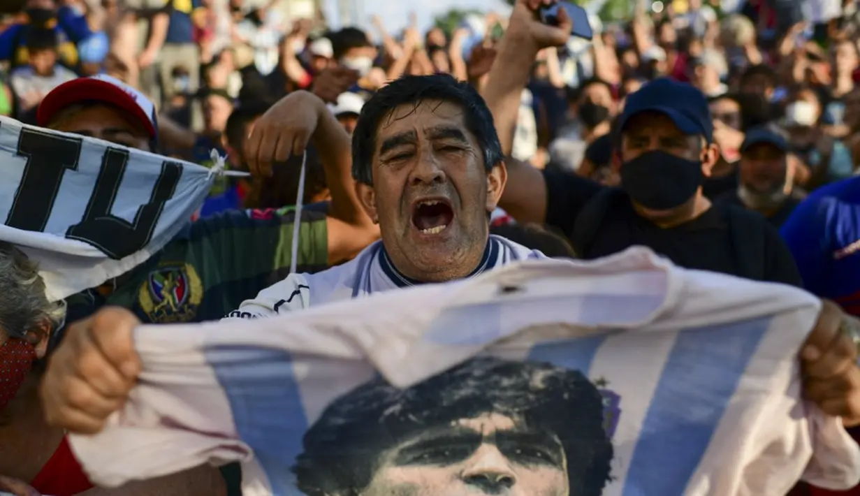 Fans berkumpul di luar kamar jenazah tempat jasad mendiang legenda sepak bola Argentina Diego Maradona akan menjalani otopsi di San Fernando, Buenos Aires, Argentina, 25 November 2020. Jenazah Diego Maradona akan disemayamkan di Istana Presiden. (RONALDO SCHEMIDT/AFP)