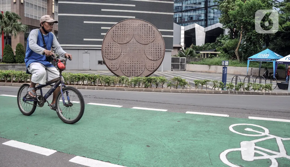 Pesepeda melintas dekat Tugu Sepeda di Jalan Jenderal Sudirman, Jakarta Pusat, Minggu (23/10/2022). Tugu Sepeda berbentuk roda setinggi 5,7 meter. (merdeka.com/Iqbal S. Nugroho)