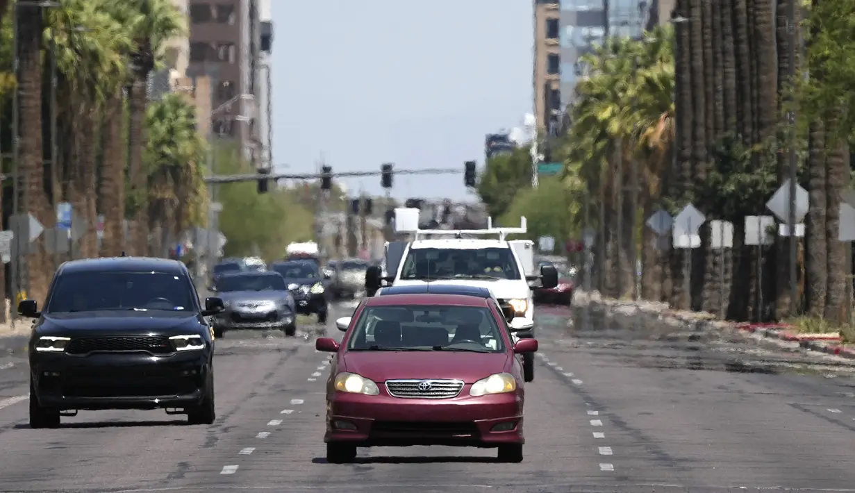 Gelombang panas naik dari trotoar saat kendaraan melaju di sepanjang jalan pusat kota saat suhu diperkirakan mencapai 115 derajat Fahrenheit di Phoenix, Selasa, 18 Juli 2023. (AP Photo/Ross D. Franklin)