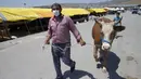 Seorang pria yang mengenakan masker menarik seekor sapi di sebuah pasar ternak di Ankara, Turki, 20 Juli 2020. Hari Raya Idul Adha di Turki akan dirayakan mulai tanggal 31 Juli hingga 3 Agustus 2020. (Xinhua/Mustafa Kaya)