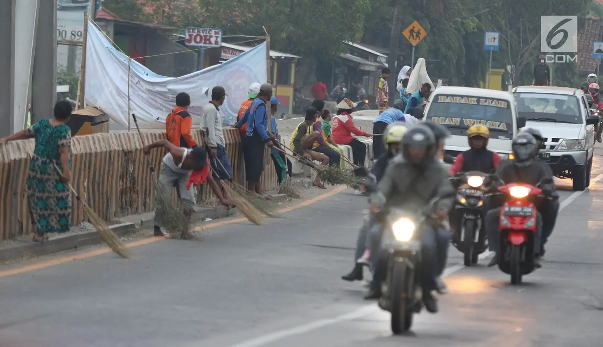 Warga membawa sapu menunggu pengguna jalan memberi sedekah dengan melempar uang di Jembatan Sewo, Jalur Pantura Sukra Indramayu, Jawa Barat, Senin (3/6/2019). Keberadaan pencari sedekah bisa membahayakan keselamatan pemudik serta pengguna jalan lainnya. (Liputan6.com/Herman Zakharia)