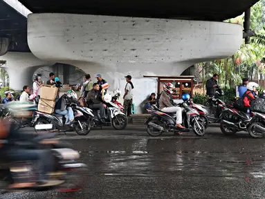 Pengendara sepeda motor berteduh di bawah flyover saat hujan turun, Jakarta, Senin (16/11). Memasuki musim hujan, polisi meminta pengendara untuk tidak berteduh di sembarang tempat, khususnya di bawah fly over. (Liputan6.com/Immanuel Antonius)