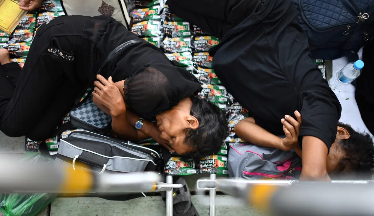 Sejumlah warga beristirahat saat menunggu pemakaman mendiang Raja Thailand Bhumibol Adulyadej di Bangkok (25/10). (AFP Photo/Roberto Schmidt)