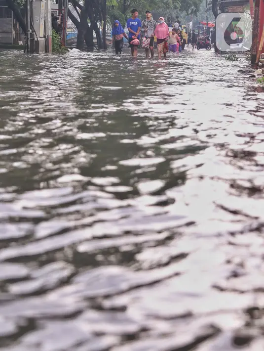 Pejalan kaki melewati banjir yang menggenangi Jalan KH. Ahmad Dahlan Cipondoh, Tangerang, Selasa (16/2/2021). Hujan deras yang melanda wilayah Tangerang mengakibatkan ruas jalan alternatif penghubung Tangerang dengan Jakarta tersebut banjir setinggi lutut orang dewasa. (Liputan6.com/Angga Yuniar)