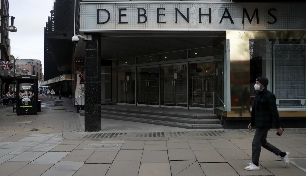 Seorang pria yang mengenakan masker berjalan melewati papan informasi virus corona di sebelah department store andalan Debenhams yang ditutup di Oxford Street di London, Sabtu (6/2/2021). Debenhams, yang berusia 242 tahun, menyatakan mereka dalam proses penutupan massal. (AP Photo/Matt Dunham)