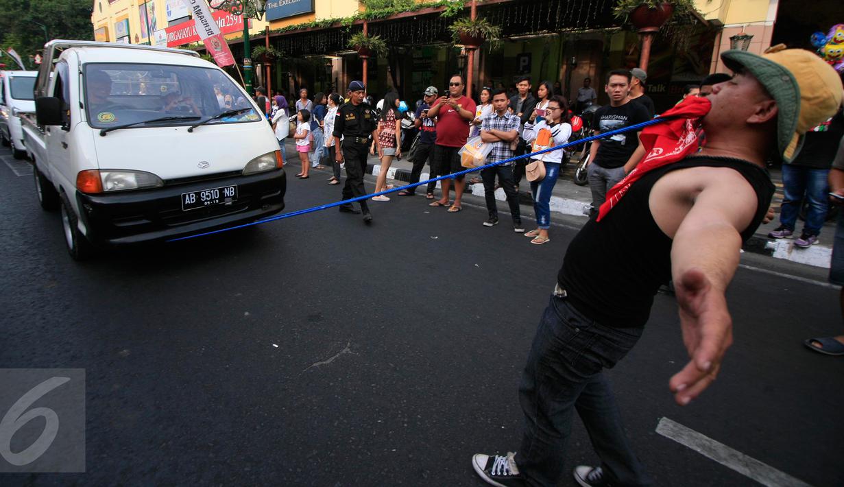 Seorang peserta karnaval menarik sebuah mobil saat mengikuti karnaval budaya Keris Summit 2015 di Jl Malioboro, Yogyakarta,  Rabu (28/10/2015). Agenda dari acara ini seperti workshop ,pameran dan penjaulan keris. (Boy T Harjanto)