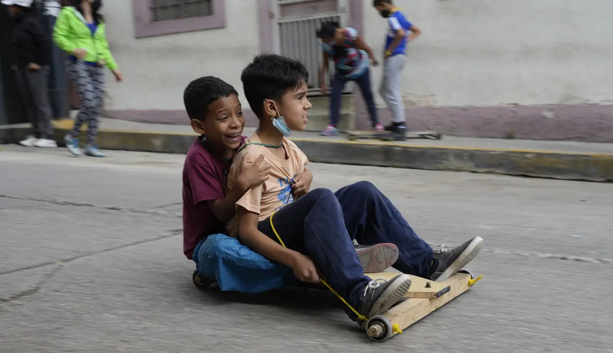 Anak-anak berpartisipasi dalam perlombaan jalanan tradisional "carruchas", sebutan untuk mobil kayu darurat di Caracas, Venezuela, Sabtu (18/12/2021). Anak laki-laki dan perempuan berusia antara 4 hingga 15 tahun berpartisipasi dalam perlombaan tersebut. (AP Photo/Ariana Cubillos)