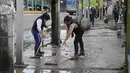 Penduduk desa membuang lumpur dari jalan setelah hujan lebat yang menyebabkan banjir di Ecatepec, Meksiko (7/9/2021).  (AFP/Claudio Cruz)