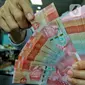 Pegawai menata mata uang rupiah di salah satu gerai penukaran mata uang di Jakarta, Kamis (5/1/2023). Nilai tukar rupiah ditutup di level Rp15.616 per dolar AS pada Kamis (5/1) sore ini. Mata uang Garuda melemah 34 poin atau minus 0,22 persen dari perdagangan sebelumnya. (Liputan6.com/Angga Yuniar)