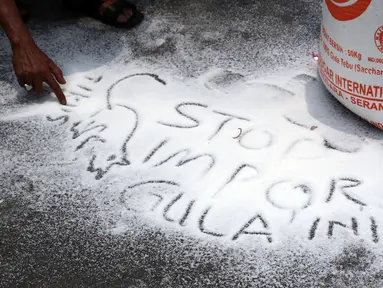 Perwakilan petani tebu menuliskan kata kata saat berunjuk rasa di sekitar depan Istana Negara, Jakarta, Selasa (16/10). Puluhan perwakilan petani tebu berunjuk rasa menuntut pemerintah menyetop impor gula. (Liputan6.com/Helmi Fithriansyah)