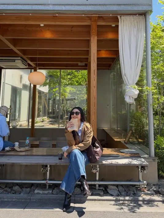 Febby juga menunjukkan gaya kasual yang tetap fashionable saat duduk santai di sebuah coffee shop. Ia mengenakan inner putih yang dipadukan jaket cokelat suede dan wide leg jeans. [@febbyrastanty].