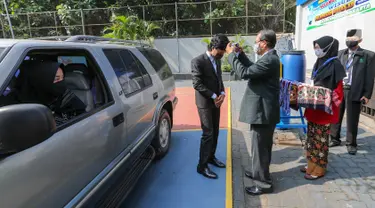 Kepala sekolah menyematkan medali kelulusan pada acara Wisuda Pelepasan Kelas XII di Madrasah Aliyah Annajah, Petukangan, Jakarta, Kamis (18/6/2020). Pandemi Covid-19, Madrasah Aliyah Annajah menerapkan Wisuda Drive Thru guna mencegah penyebaran virus Covid-19. (Liputan6.com/Fery Pradolo)