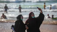 Wanita Palestina berselfie selama liburan Idul Fitri, di pantai laut Mediterania di Tel Aviv, Israel (25/5/2020).  Idul Fitri menandai akhir bulan suci Ramadhan, perayaan tiga hari yang biasanya menggembirakan telah berkurang secara signifikan karena pandemi coronavirus. (AP Photo/Oded Balilty)