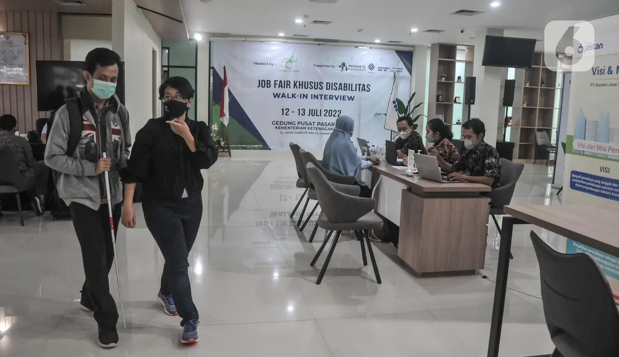 Petugas mendampingi penyandang tunanetra saat mengikuti walk in interview Job Fair Khusus Disabilitas di Gedung Pusat Pasar Kerja, Kementerian Ketenagakerjaan, Jakarta, Rabu (13/7/2022). Job fair ini diikuti 6 perusahaan dan diharapkan dapat melibatkan 200 pencari kerja. (merdeka.com/Iqbal S. Nugroho)