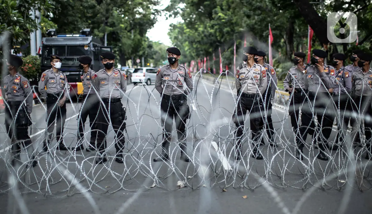 Polisi berjaga dari balik kawat berduri saat massa yang tergabung dalam BEM Nusantara menggelar aksi di kawasan Patung Kuda, Jakarta, Kamis (1/9/2022). Dalam aksinya mereka menolak naiknya harga BBM yang dinilai merugikan rakyat kecil. (Liputan6.com/Faizal Fanani)