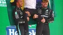 Pembalap Mercedes Lewis Hamilton (kiri) dan pembalap Mercedes Valtteri Bottas (kanan) memegang seorang engineer tim di pundak mereka saat merayakan posisi pertama dan ketiga pada Formula 1 Grand Prix di Sirkuit Interlagos, Sao Paulo, Brasil, 14 November 2021. (Lars Baron, Pool Photo via AP)