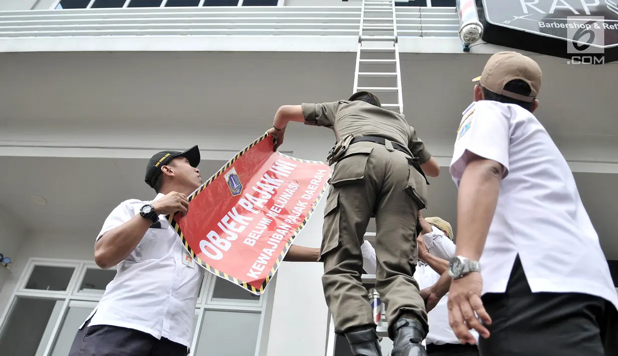 Tim gabungan dari Badan Pelayanan Pajak, Kecamatan Cempaka Putih, dan Satpol PP bersiap memasangkan stiker tunggak pajak di salah satu kios Green Pramuka Square Mall, Jakarta, Rabu (7/11). (Merdeka.com/Iqbal S. Nugroho)