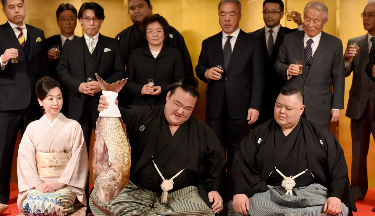 Pegulat sumo Jepang, Kisenosato foto bersama saat mendapat hidangan ikan red sea bream merayakan kemenangannya dalam upacara yang berlangsung di Tokyo, Jepang, Rabu (25/1). (AFP Photo/Toru Yamanaka) 