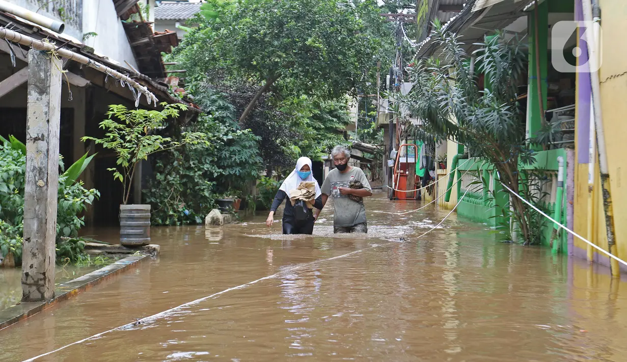 Warga berjalan melintasi banjir yang merendam kawasan Cipinang Melayu, Jakarta Timur, Jumat (19/2/2021). Banjir di kawasan tersebut akibat curah hujan yang tinggi dan meluapnya air dari Kali Sunter. (Liputan6.com/Herman Zakharia)