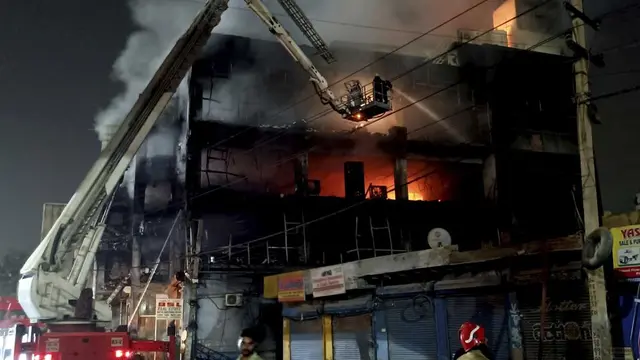 Petugas pemadam kebakaran berusaha memadamkan api di sebuah gedung berlantai empat, di New Delhi, India, Jumat, 13 Mei 2022. (Foto AP/Dinesh Joshi)