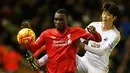 Penyerang Liverpool, Christian Benteke (depan) berusaha mengontrol bola dari kawalan gelandang Swansea, Ki Sung Yeung pada lanjutan liga inggris di Stadion Anfield, Inggris (29/11). Liverpool menang atas Swansea dengan skor 1-0. (Reuters/Phil Noble)