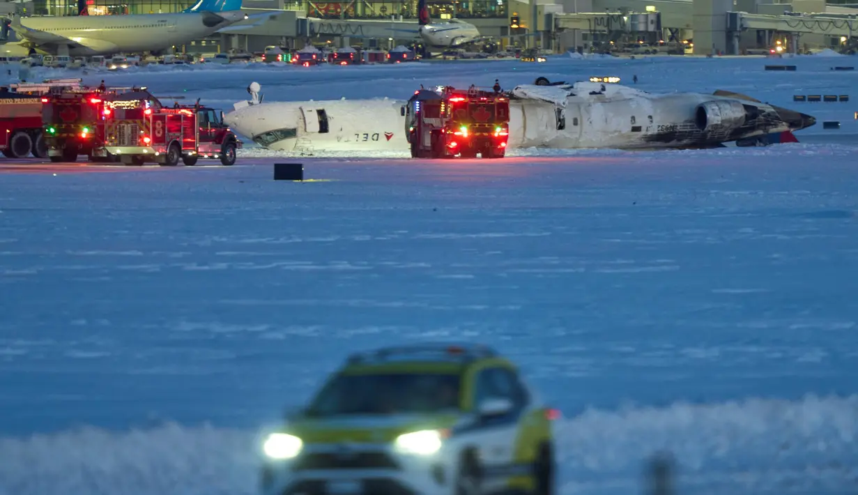 Pesawat Delta Air Lines terbalik setelah mendarat di Bandara Toronto Pearson, Kanada saat cuaca berangin yang menyusul badai salju pada Senin (17/2/2025). (Geoff Robins/AFP)
