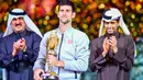 Petenis Serbia, Novak Djokovic memegang trofi Qatar Open 2017 usai menaklukkan petenis Skotlandia, Andy Murray dalam final turnamen Qatar Terbuka di Doha, Sabtu (7/1). Ini merupakan gelar ke-67 buat Djokovic di tur ATP.  (AP Photo/Alexandra Panagiotidou)