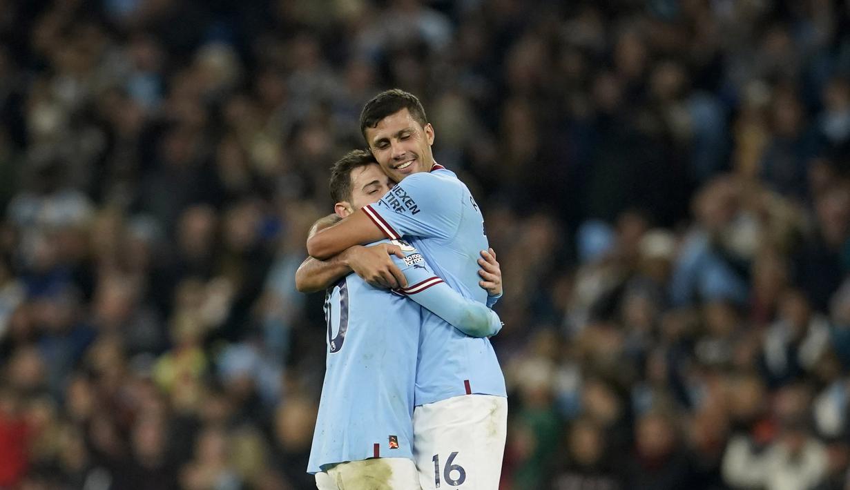 Pemain Manchester City, Bernardo Silva dan Rodrigo berpelukan setelah menaklukkan Arsenal pada laga Liga Inggris di Stadion Etihad, Kamis (27/4/2023). Kemenangan ini membuat selisih poin kedua tim hanya berjarak dua angka. Man City masih di peringkat ke-2 dengan 73 poin. (AP Photo/Dave Thompson)