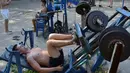 Seorang pria mendorong sebuah alat berat menggunakan kakinya di sebuah gym outdoor di Ibu Kota Ukraina, Kiev, 18 Agustus 2017. Alat olahraga di taman Kachalka itu dibuat seorang teknisi bernama Yuri Kook pada dekade 1970-an. (GENYA SAVILOV/AFP)