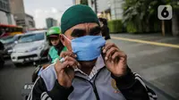 Warga mengenakan masker yang dibagikan relawan di Bundaran HI, Jakarta, Selasa (17/3/2020). Sebanyak 3.000 masker dibagikan gratis kepada pengguna jalan sebagai salah satu bentuk keprihatinan sekaligus berpartisipasi dalam upaya mencegah penyebaran virus corona COVID-19. (Liputan6.com/Faizal Fanani)