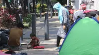 Pencari suaka beraktivitas di trotoar kantor UNHCR, Jalan Kebon Sirih, Jakarta, Sabtu (1/5/2021). Para pencari suaka itu menuntut Komisi Tinggi PBB untuk Pengungsi (UNHCR) meminta kejelasan atas status dan memperhatikan nasib mereka selama hidup di Indonesia. (Liputan6.com/Herman Zakharia)