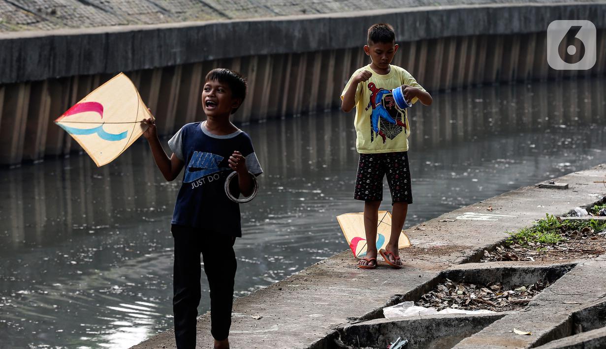 Anak-anak bermain layang-layang di pinggir kali Jalan Inspeksi Jakarta Barat, Rabu (12/7/2023). Meski berbahaya, mereka tetap menikmati bermain di pinggir kali tersebut. (Liputan6.com/Johan Tallo)