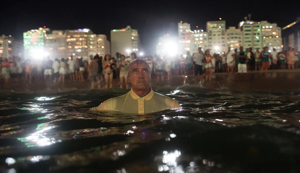 Seorang pria menyaksikan pesta kembang api menyambut Tahun Baru 2019 di Pantai Copacabana, Rio de Janeiro, Brasil, Selasa (1/1). (AP Photo/Leo Correa)