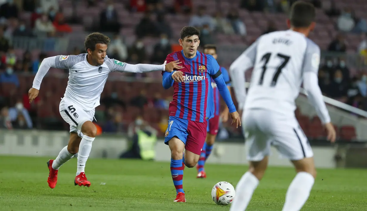 Gelandang Granada Luis Milla (kiri) berebut bola dengan penyerang Barcelona, Yusuf Demir pada lanjutan La Liga di Camp Nou, Selasa (21/9/2021) dini hari WIB. Barcelona dipaksa bermain imbang 1-1 oleh tamunya Granada. (AP Photo/Joan Monfort)