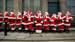 Sejumlah pria mengenakan kostum Santa Claus berbaris saat sesi pemotretan di Ragged School Museum di London (16/11). Sekolah ini juga mengajarkan teknik mengembus serta tertawa ho ho ho khas Santa Claus. (AP Photo/Matt Dunham)