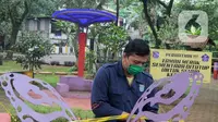 Petugas Dinas Lingkungan Hidup dan Kebersihan (DLHK) Kota Depok memasang garis larangan melintas umum di Taman Merak, Limo, Depok, Senin (25/1/2021). Pembatasan dan penutupan taman tersebut dilakukan dalam rangka Pemberlakuan Pembatasan Kegiatan Masyarakat (PPKM). (merdeka.com/Arie Basuki)