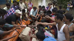 Petugas membagikan makanan kepada korban banjir di Gauhati, India, Rabu (14/6). Angin monsun yang mendatangi India berdampak pada tingginya curah hujan yang menyebabkan banjir. (AP Photo / Anupam Nath)