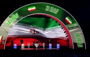 Asisten pengundian, Tom Brady, Asisten pengundian, Shaquille O’Neal, Konduktor Samantha Johnson, Legenda FIFA, Rio Ferdinand, Asisten pengundian, Aaron Judge, dan Asisten pengundian, Wayne Gretzky berdiri di atas panggung saat Iran ditampilkan di layar selama Pengundian Resmi Piala Dunia 2026 di John F. Kennedy Center for the Performing Arts pada 5 Desember 2025 di Washington, DC. (Kevin Dietsch/Getty Images via AFP)
