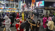Para pejalan kaki dengan kostum berpose untuk foto ketika ribuan orang berkumpul di distrik Shibuya, area pertemuan populer untuk Halloween, di Tokyo, Minggu (31/10/2021). Daerah di sekitar Stasiun Shibuya dipadati anak-anak muda yang berdandan selama Halloween setiap tahun. (AP Photo/Kiichiro Sato)