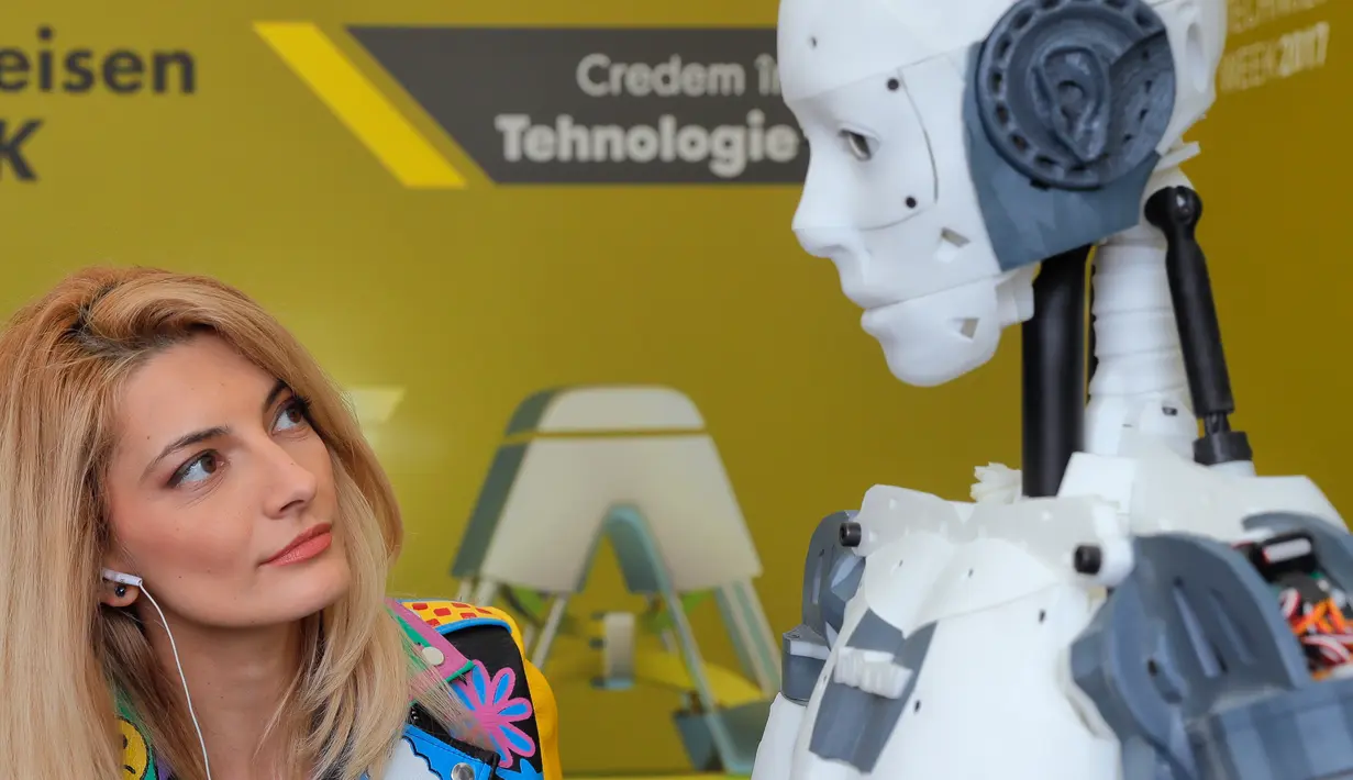 Seorang reporter melihat robot InMoov rancangan Gael Langevin dalam pameran teknologi Bucharest, Romania (26/5). Robot ini dapat diprogram untuk berbicara bahasa Inggris, Spanyol, Prancis, Rusia dan Belanda (AP Photo / Vadim Ghirda)